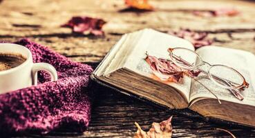 tasse de café vieux livre des lunettes et l'automne feuilles. photo