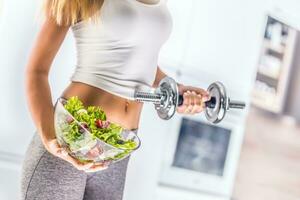 femme en portant bol de Frais légume salade et haltère. photo