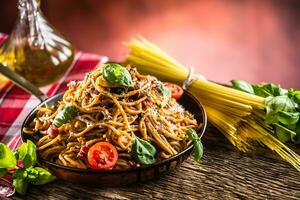 italien Pâtes spaghetti avec tomate sauce olive pétrole basilic et Parmesan fromage dans vieux la poêle photo