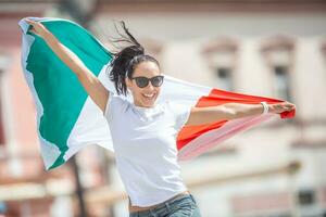 content Jeune femme fête la victoire de Italie sur une rue en portant une drapeau et sauter de joie photo