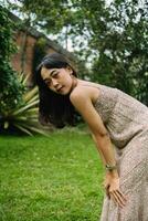 un asiatique femme dans une crème coloré robe permanent très jolie derrière le maison photo