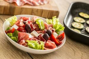 Frais salade salade avec grillé Zucchini coppa di parme jambon feta fromage Olives tomates et olive pétrole photo