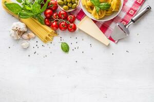 italien nourriture cuisine et Ingrédients sur blanc béton tableau. spaghetti tagliatelles Olives olive pétrole tomates Parmesan fromage Ail poivre et basilic feuilles et à carreaux nappe de table. photo