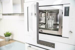 intégré four micro onde four dans le cuisine avec une tasse de pur l'eau photo