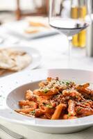 Penne alla arrabiata servi avec blanc du vin dans une restaurant environnement photo