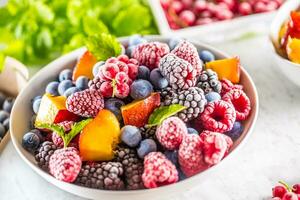 congelé des fruits myrtilles la mûre framboise rouge groseille pêche et herbes mélisse photo