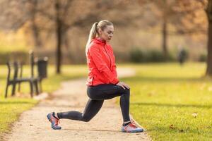 une Jeune femme réchauffe en haut avant le jogging et réchauffe en haut sa jambe muscles photo