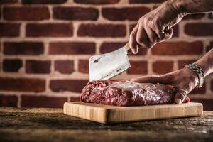 Boucher homme mains Coupe brut du boeuf steak dans boucherie photo