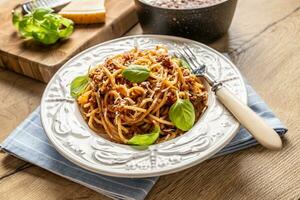 italien Pâtes spaghetti bolognaise servi sur blanc assiette avec Parmesan fromage et basilic photo