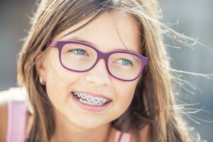 portrait de content souriant fille avec dentaire un appareil dentaire et des lunettes photo