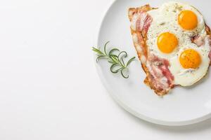 jambon et des œufs. Bacon et des œufs. salé Oeuf avec poivre sur blanc plaque. Anglais petit déjeuner photo