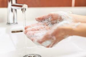 la lessive mains avec l'eau et liquide savon dans le salle de bains. hygiène antivirus concept photo