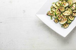 courgette. grillé Zucchini avec rouge pimenter sur blanc assiette photo