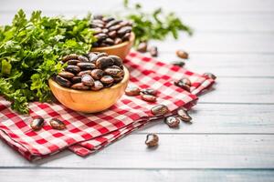 non cuit des haricots dans en bois quilles avec persil herbes sur cuisine table photo