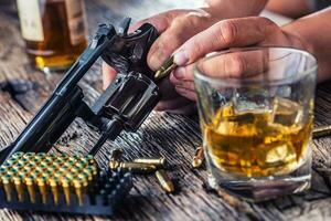 homme mains en portant pistolet et de l'alcool verre sur le table photo