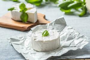 Camembert ou Brie fromage avec basilic feuilles sur table photo