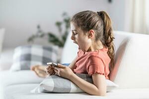 fille à la recherche dans sa téléphone bâille de étant fatigué ou ennuyé comme elle est assis à Accueil sur une canapé photo