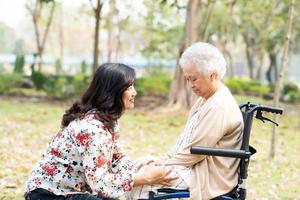Patiente asiatique âgée ou âgée avec soin, aide et soutien heureux en fauteuil roulant dans le parc en vacances, concept médical fort et sain.