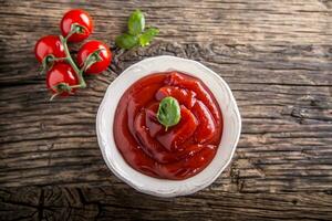 ketchup ou tomate sauce dans blanc bol et Cerise tomates sur en bois table photo