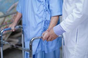 un médecin aide une femme âgée ou âgée asiatique à marcher avec une marchette à l'hôpital de soins infirmiers. photo