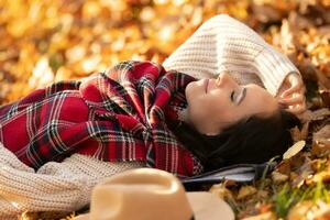 insouciant magnifique brunette mensonge dans le parc relaxant pendant ensoleillé l'automne le coucher du soleil photo