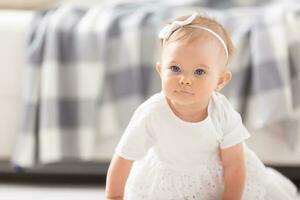 petit fille bambin rampant dans blanc robe sur le sol dans le vivant pièce photo