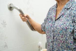 Une patiente asiatique âgée ou âgée utilise la sécurité de la poignée de la salle de bain des toilettes dans la salle d'hôpital de soins infirmiers, concept médical solide et sain. photo