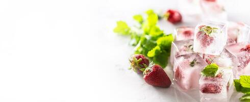 des fraises congelé dans la glace cubes avec mélisse feuilles, bannière avec copie espace photo