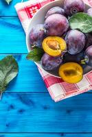 prunes. Frais juteux prunes dans une bol sur une en bois ou béton planche photo