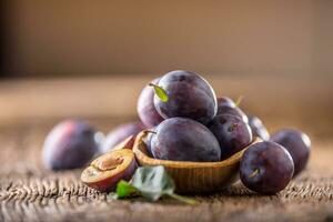 prunes. Frais juteux prunes dans une bol sur une en bois ou béton planche photo