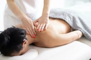 masseur communiqués le tension de une rigide épaule de une femelle client dans le masser studio photo