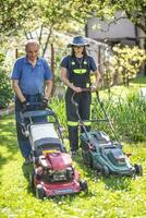 personnes âgées grand-père enseignement sa petite fille Comment à utilisation tondeuse et Couper herbe. elles ou ils travail dans le rustique jardin dans le village photo