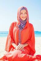 magnifique musulman caucasien russe femme portant rouge robe relaxant sur une plage photo