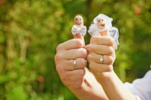 une homme et femme en portant doigt marionnettes avec mariage anneaux photo