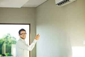 une homme est permanent dans de face de une mur monté air Conditionneur photo