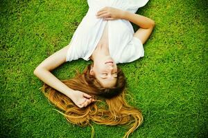 une femme pose sur le herbe avec sa cheveux vers le bas photo