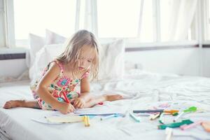 peu blond fille dessin séance sur le lit photo