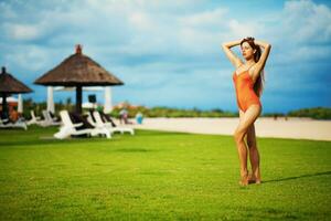 une femme dans un Orange maillot de bain permanent sur le herbe photo