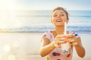 une femme en portant une bulle thé boisson sur le plage photo