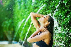 une femme dans une bikini est permanent en dessous de une cascade photo