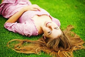 une femme pose sur le herbe avec sa cheveux vers le bas photo