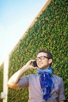 une homme dans des lunettes et une écharpe parlant sur une cellule téléphone photo