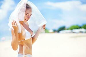 une femme dans une bikini et blanc voile sur le plage photo