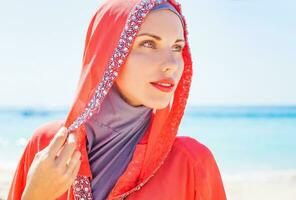 magnifique musulman caucasien russe femme portant rouge robe relaxant sur une plage photo