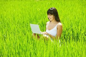 femme avec une portable dans une vert champ. travail à distance concept photo