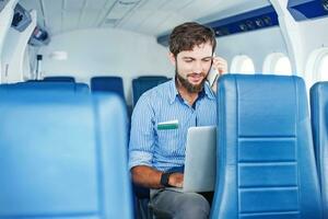 une homme séance dans un avion avec le sien portable photo
