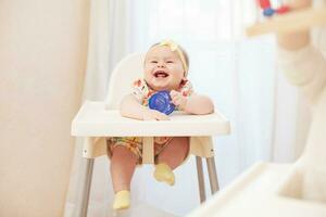 une bébé dans une haute chaise en riant photo