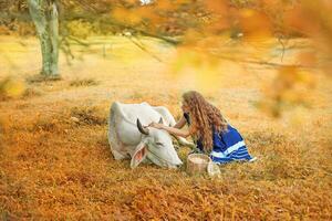 une femme est caresse une vache dans le herbe photo