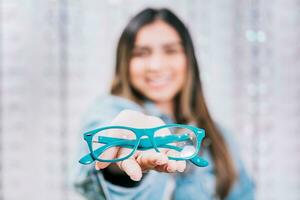 fille mains montrant certains des lunettes dans une magasin. acheteur montrant des lunettes dans une magasin. content fille en portant des lunettes dans paume main dans une boutique photo