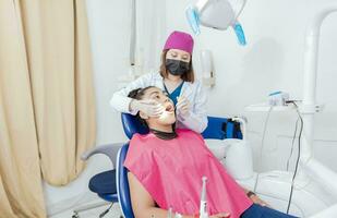 femelle dentiste avec sonde et dentaire miroir examiner bouche à mensonge patient. santé et dentaire se soucier concept, dentiste médecin examiner bouche à femelle patient mensonge sur chaise photo